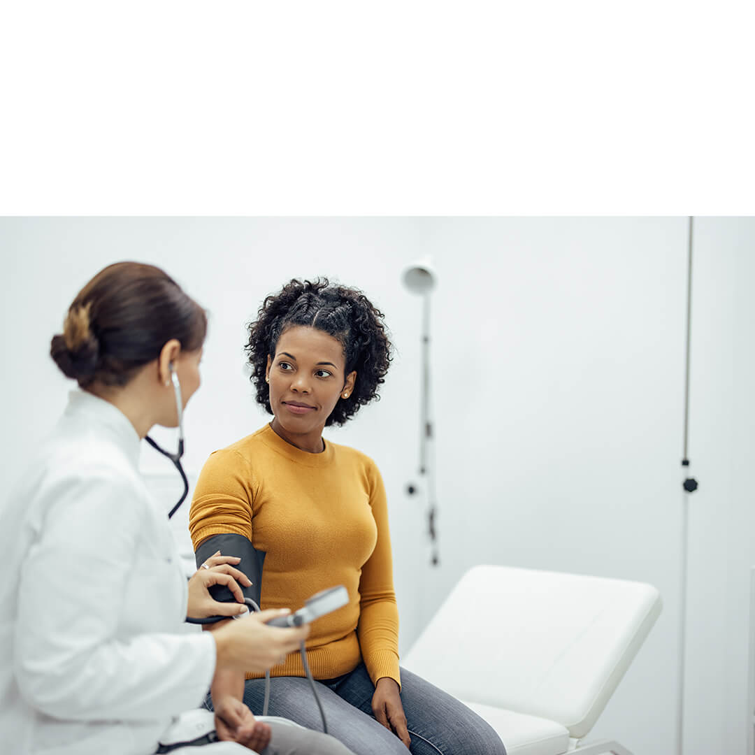 A healthcare provider measures a patient’s blood pressure in a bright clinic room, symbolizing cancer care locations